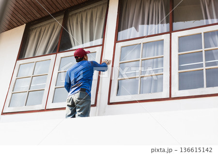 Construction worker sanding and preparing exterior of a residential building. Construction worker sanding and preparing exterior of a residential building. 136615142