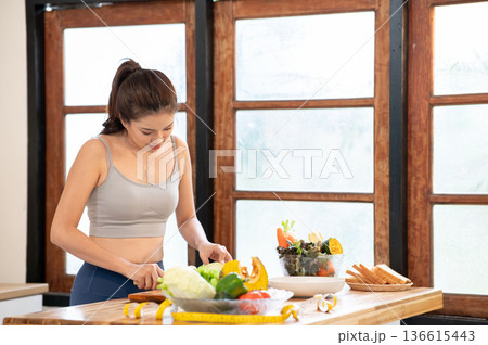 Asian woman in sportswear hold knife cutting vegetables on chopping board at kitchen cooking counter 136615443