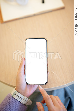 Woman hand holding smartphone finger pointing at white screen watching reading sitting at cafe table 136615700