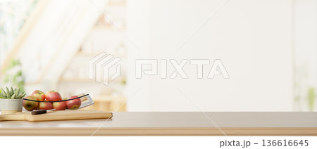 Apples in glass plate aside knife over cutting board on wooden counter across a blurred living room. Apples in glass plate aside knife over cutting board on wooden counter across a blurred living room. 136616645