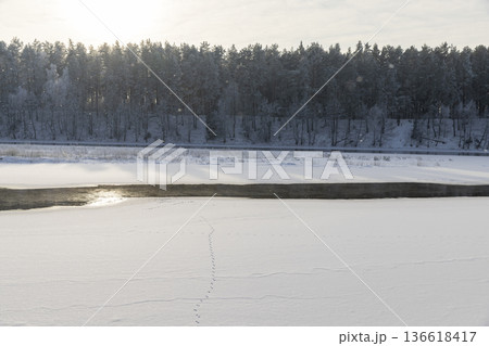 a wide river that is frozen in winter after frosts, a small part of the river that is not frozen after severe frosts, the rest of the river is covered with ice and fresh snow a wide river that is frozen in winter after frosts, a small part of the river that is not frozen after severe frosts, the rest of the river is covered with ice and fresh snow 136618417