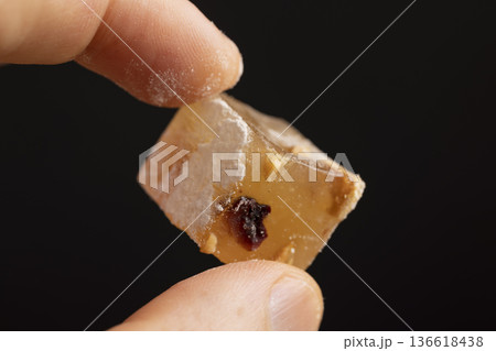 hold a soft and fresh Turkish delight sprinkled with a small amount of powdered white sugar, cubic sweet white soft pieces of Turkish delight with nuts and fruits, hold sweetness in hands 136618438