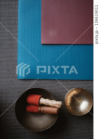 Yoga Mat and Singing Bowl with Mallets on Textile Surface Yoga Mat and Singing Bowl with Mallets on Textile Surface 136619011