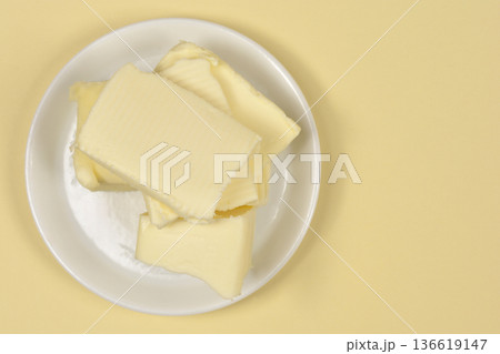 Slices of fresh butter on a white plate 136619147