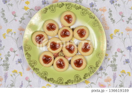 Baked thumbprint cookies with jam on a green plate Baked thumbprint cookies with jam on a green plate 136619189