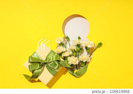 Yellow backdrop featuring flowers and a gift box for celebration Yellow backdrop featuring flowers and a gift box for celebration 136619908