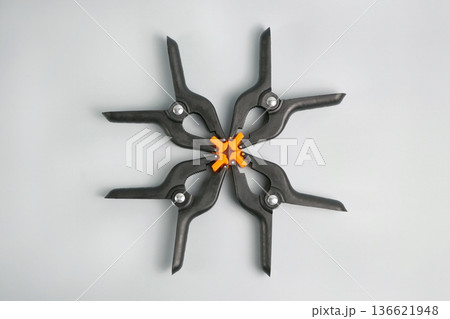 Four black plastic spring clamps with orange pads arranged in circle, isolated on white. Strong grip hand tools for woodworking, DIY, repair and workshop use Four black plastic spring clamps with orange pads arranged in circle, isolated on white. Strong grip hand tools for woodworking, DIY, repair and workshop use 136621948
