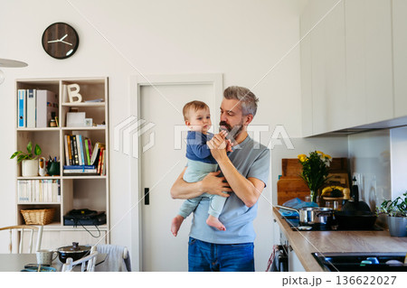 Dad holding his little toddler son in arms. 136622027