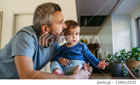 Father with little toddler son looking out of window. 136622035