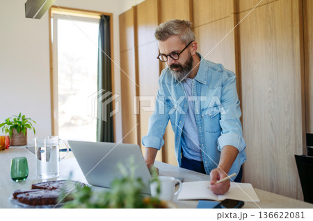 Man working from home office, working on laptop. Man working from home office, working on laptop. 136622081