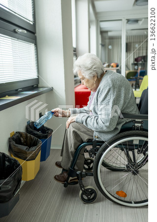 Senior woman in wheelchair sorting plastic bottle for recycling. Senior woman in wheelchair sorting plastic bottle for recycling. 136622100