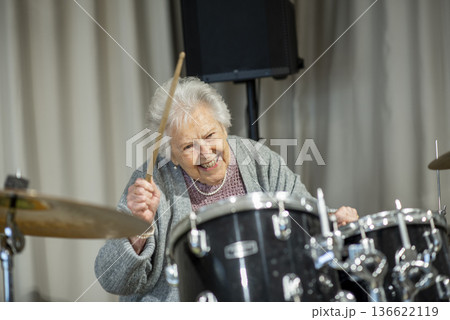Senior woman enjoying her hobby playing drums. Senior woman enjoying her hobby playing drums. 136622119