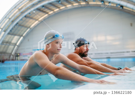 Father and teenage son enjoying swim training together. Father and teenage son enjoying swim training together. 136622180