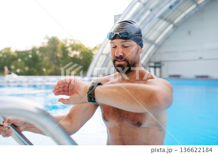 Male swimmer is preparing for swim in pool. 136622184
