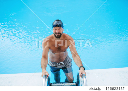 Male swimmer is preparing for swim in pool. Male swimmer is preparing for swim in pool. 136622185