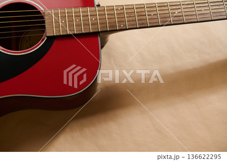 Red acoustic guitar close-up illustrating guitar maintenance, string adjustment and repair concepts for tuning, restringing and careful instrument care. Red acoustic guitar close-up illustrating guitar maintenance, string adjustment and repair concepts for tuning, restringing and careful instrument care. 136622295