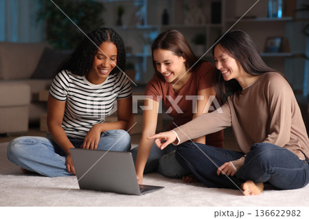 Three happy diverse friends using laptop in the night 136622982