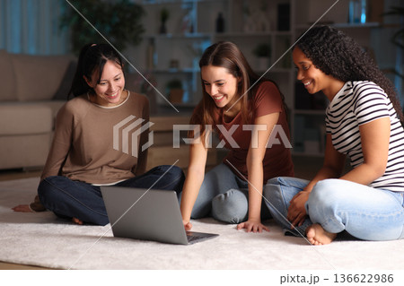 Three diverse happy friends checking laptop in the night 136622986