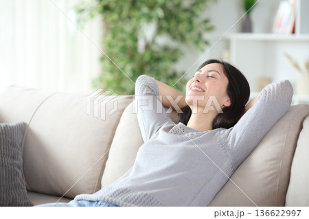 Happy asian woman resting on comfortable sofa Happy asian woman resting on comfortable sofa 136622997
