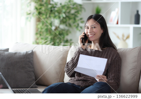Happy asian woman talking on phone about letter looking at you 136622999