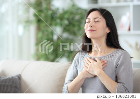 Single asian woman doing breathing exercises at home 136623003