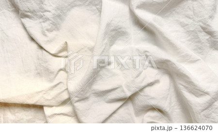 elegant crumpled white linen fabric texture unfolds in soft waves for minimalist wallpaper or subtle banner overlay 136624070