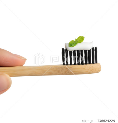 Eco-conscious concept, hand presenting a natural bamboo toothbrush with fresh mint toothpaste, isolated for dental hygiene and green lifestyle themes 136624229