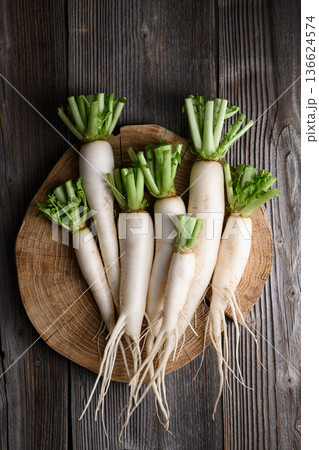 Daikon radish with green leaves on wooden cutting board Daikon radish with green leaves on wooden cutting board 136624574