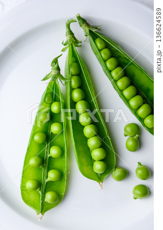 Fresh green peas in pods arranged on a white plate Fresh green peas in pods arranged on a white plate 136624589