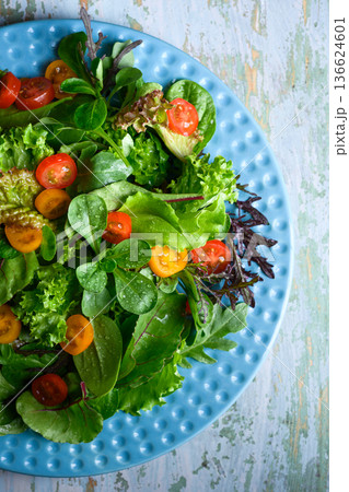 Fresh mixed salad with cherry tomatoes on blue ceramic plate Fresh mixed salad with cherry tomatoes on blue ceramic plate 136624601