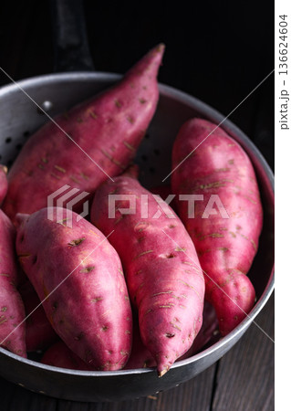 Fresh sweet potatoes in bowl on dark surface 136624604