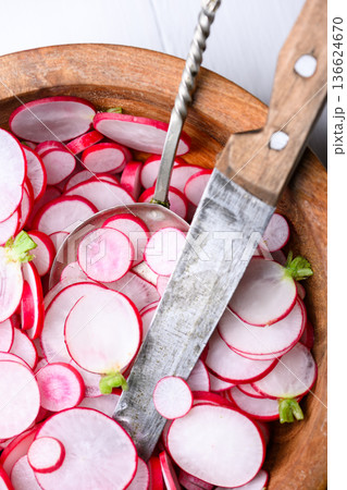 Radish slices in wooden bowl with kitchen knife Radish slices in wooden bowl with kitchen knife 136624670