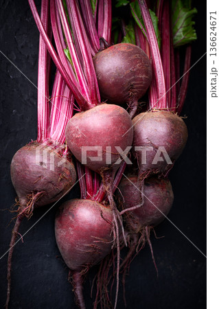 Raw beetroot bunch with leaves on dark surface Raw beetroot bunch with leaves on dark surface 136624671