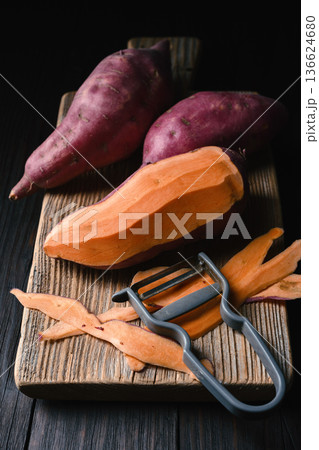 Sweet potato sliced on wooden board with peeler 136624680