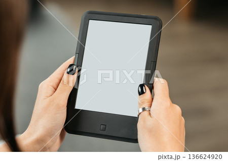 Person holding an e-reader in a cozy room during evening time Person holding an e-reader in a cozy room during evening time 136624920