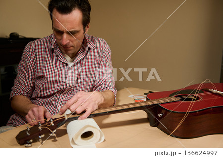 Man Changing Guitar Strings Repairing And Adjusting Acoustic Guitar For Maintenance And Tuning 136624997