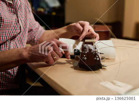 Man Changing Guitar Strings and Tuning Headstock During Guitar Maintenance and Repair Man Changing Guitar Strings and Tuning Headstock During Guitar Maintenance and Repair 136625001