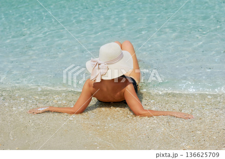 back view of young beautiful woman with coconut relaxing at sunny tropical beach back view of young beautiful woman with coconut relaxing at sunny tropical beach 136625709