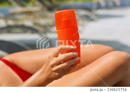 Female hand holding sunscreen cream  bottle.Sunbath protection. 136625756
