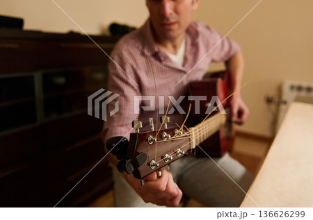Man Changing Guitar Strings and Adjusting Tuning for Maintenance and Repair Man Changing Guitar Strings and Adjusting Tuning for Maintenance and Repair 136626299