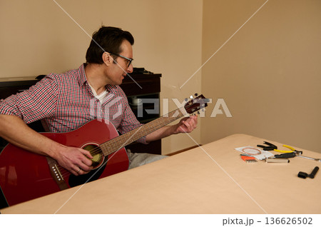 Man Changing Guitar Strings at Home - Guitar Maintenance, Repair and Tuning 136626502