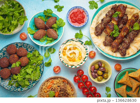 Middle eastern or Arab dishes and assorted meze on light beige background. Meat kebab, falafel, hummus, sambusak, rice, kibbeh, pita. Halal food. Lebanese cuisine Middle eastern or Arab dishes and assorted meze on light beige background. Meat kebab, falafel, hummus, sambusak, rice, kibbeh, pita. Halal food. Lebanese cuisine 136628630