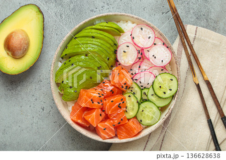 Salmon poke bowl with avocado, radish, cucumber and rice on grey background top view 136628638
