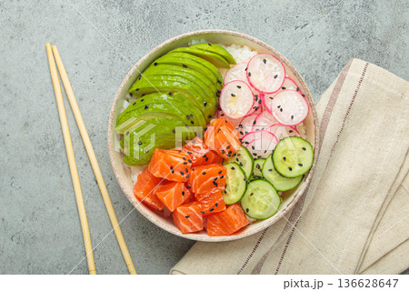Salmon poke bowl with avocado, radish, cucumber and rice on grey background top view Salmon poke bowl with avocado, radish, cucumber and rice on grey background top view 136628647