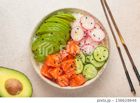 Salmon poke bowl with avocado, radish, cucumber and rice on light beige background top view 136628648
