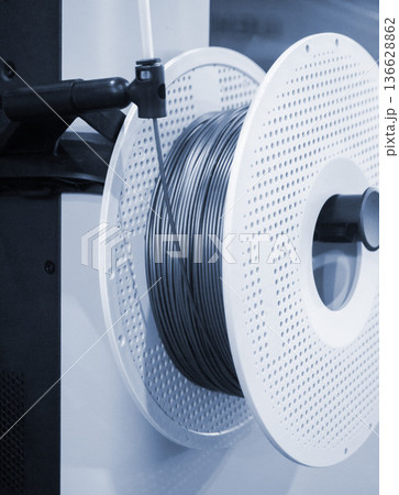 Spool of plastic wire for 3D printing. Spool with blue plastic close-up. Component for 3d printing. Printing accessories. Concept modern 3D printing technology. Additive progressive FDM technologies 136628862