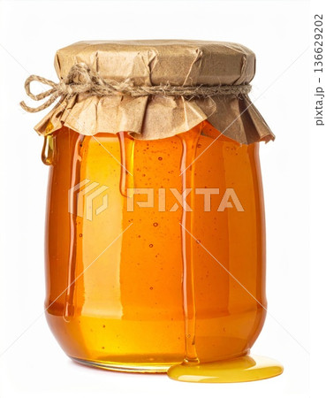 Golden Honey Drips Down Glass Jar with Brown Paper Lid and Twine on White Background 136629202