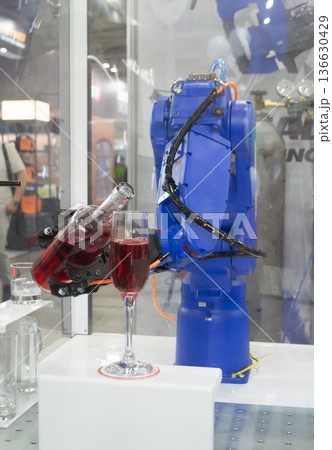Robotic manipulators. Robot pouring liquid drink from bottle into glass. Industrial robot. Robot arm hand. Industrial manipulators for variety welding, material handling, palletizing. Robotization Robotic manipulators. Robot pouring liquid drink from bottle into glass. Industrial robot. Robot arm hand. Industrial manipulators for variety welding, material handling, palletizing. Robotization 136630429