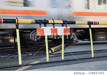 閉まっている遮断機と踏切を通過する電車 136631303