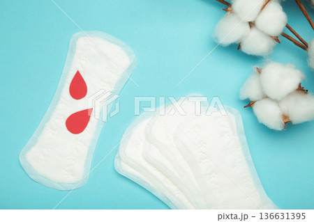 Sanitary pad with cotton flower on blue background. Daily feminine hygiene product. Sanitary pad with cotton flower on blue background. Daily feminine hygiene product. 136631395